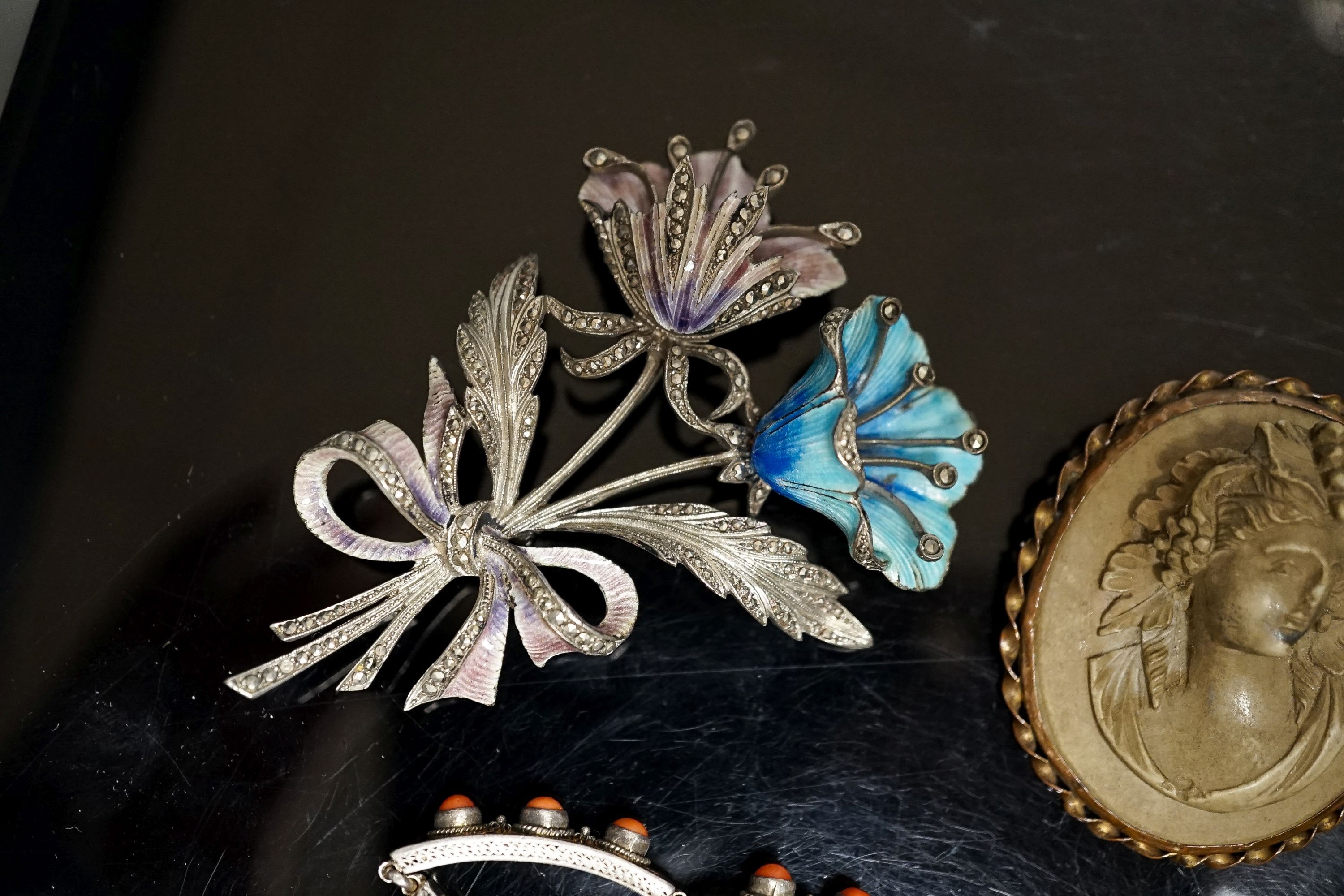 A 19th-century Lava cameo brooch, 49mm, a marcasite and enamel floral spray brooch and a coral mounted white metal bracelet.